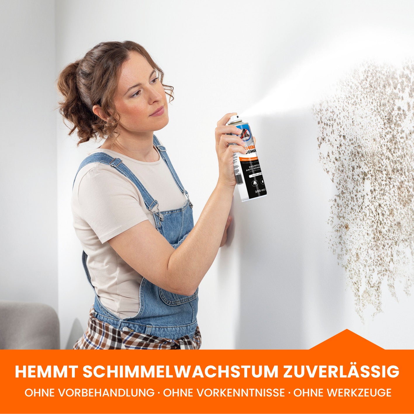 Eine Frau nutzt die Spraydose und übersprüht Schimmel.